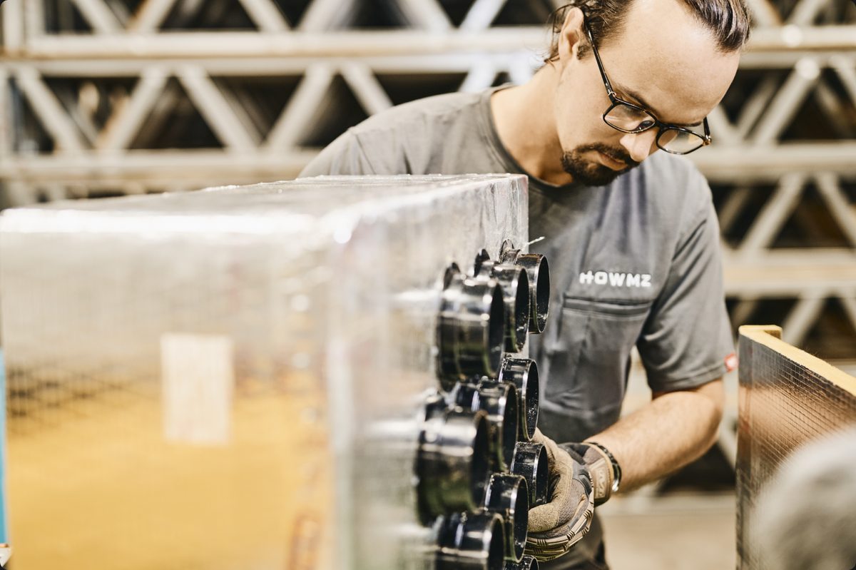 A technician fitting the energy-recovery ventilation manifold to a HOWMZ panel